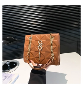 Detailed view of brown quilted bag featuring a gold SOS buckle and fine fringe accents