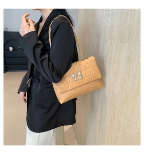 Detailed view of apricot quilted PU crossbody bag with silver bow buckle on model
