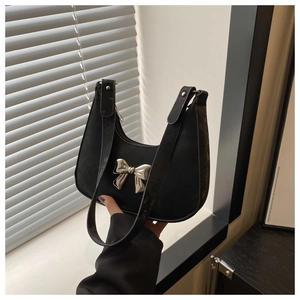 Detail of black suede crescent bag with silver metallic bow and elegant shoulder strap