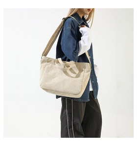 Detail of beige corduroy tote bag showing ribbed texture and long shoulder strap on model