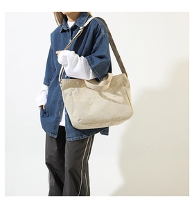 Detail of beige corduroy tote bag featuring embossed FASHION text and adjustable straps