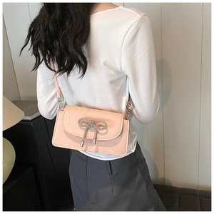 Detail view of a pink patent leather crossbody bag featuring a sparkling bow-knot decoration