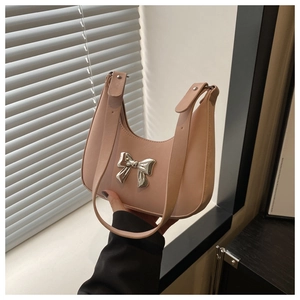 Detail of peach pink leather crescent bag with a silver metallic bow decoration