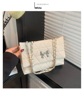 Detail of white quilted crossbody bag with silver bow accent and elegant chain strap