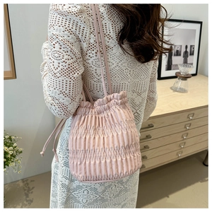 Pink drawstring bucket bag with vertical pleated texture shown in a lifestyle setting