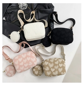 Detail view of heart-embossed crossbody bags in four colors with matching coin purses