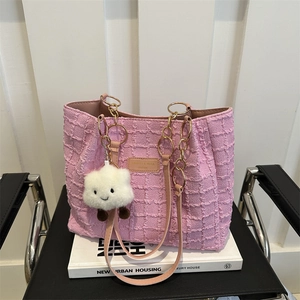 Sac cabas en tweed rose avec chaîne dorée et breloque nuage en peluche sur chaise