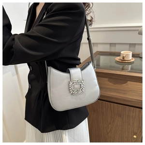 Chic silver baguette bag with oversized rhinestone buckle worn over a black blazer