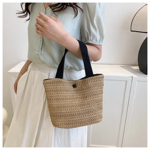Détail d'un sac cabas tissé avec anses en tissu noir et fermeture à bouton