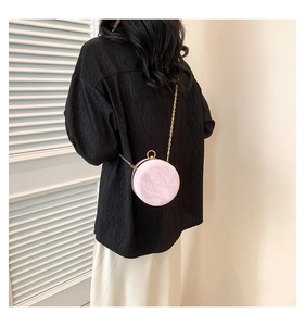 Detail view of the pink marble-textured round box bag with gold chain strap worn on back