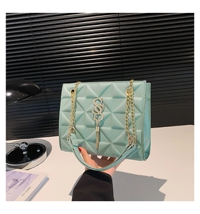 Detail of mint green quilted bag with gold SSS logo, tassel, and metallic chain strap