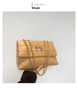 Detail of khaki quilted cross-body bag featuring a metallic bow buckle and chain strap