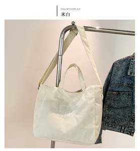 Detail view of cream corduroy tote bag with Fashion embroidery and adjustable strap