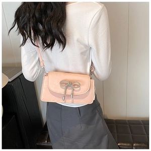 Detail view of pink crossbody bag with rhinestone bow worn by model from behind