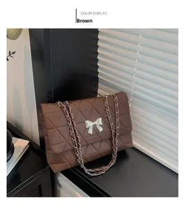 Detailed texture of brown quilted PU leather bag with silver metal bow and chain strap