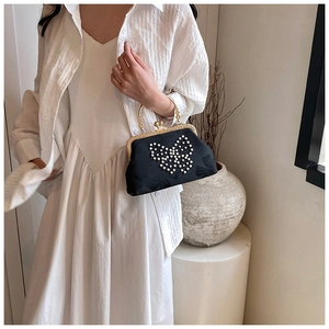 Detail of black silk clutch with pearl butterfly pattern and golden round metal handle