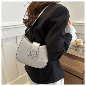 Détail du sac baguette en satin argenté avec boucle luxueuse en strass carrés sur l'épaule