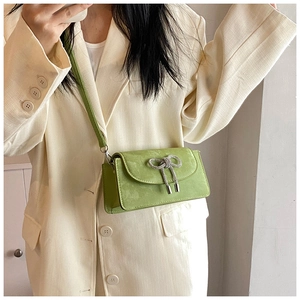 Detail of green suede crossbody bag featuring a sparkling rhinestone bow on the flap