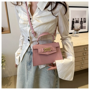 Pink faux leather trapezoid crossbody bag with elegant gold interlocking metal clasp