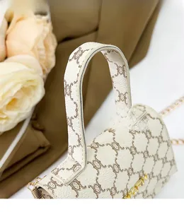Detail of cream crossbody bag with cat patterns and gold chain strap and handle