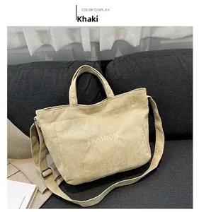 Close-up of khaki corduroy tote bag with 'FASHION' embroidery on a gray sofa