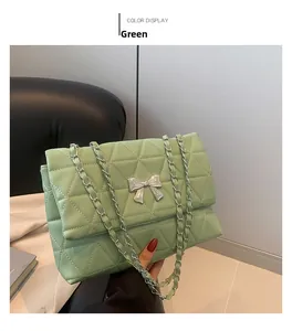 Close-up of green quilted shoulder bag with silver bow lock and chain strap