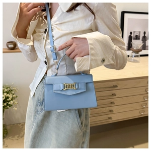 Detail of light blue crossbody bag featuring a golden chain buckle and shiny texture