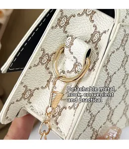 Macro view of golden hardware hook and chain on cat print white leather bag