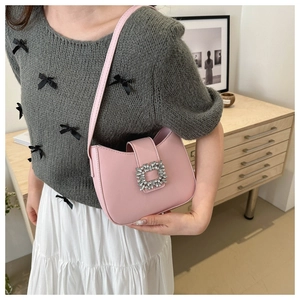 Pink underarm baguette bag with sparkling crystal buckle shown in an elegant setting