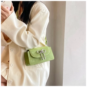 Detail of light green crossbody bag featuring a silver rhinestone bow on flap cover
