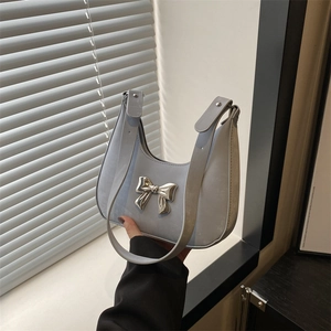 Light blue crescent hobo bag featuring a large silver metal bow and wide shoulder strap