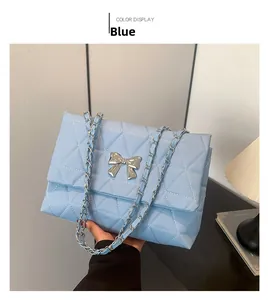Close-up of light blue quilted crossbody bag with silver bow detail and chain strap