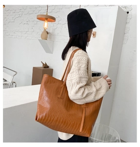 Sac cabas marron motif crocodile porté par un mannequin dans un intérieur moderne