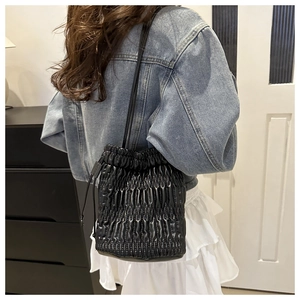 Detail of black pleated leather bucket bag with drawstring and fine matelasse texture