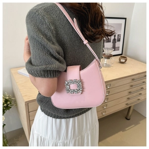 Detail of a pink baguette bag with a square crystal buckle worn by a model