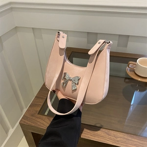 Chic pink bowknot crescent handbag with metallic detail in minimalist lifestyle setting
