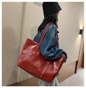 Détail d'un sac cabas rouge à motif crocodile porté à l'épaule par un mannequin