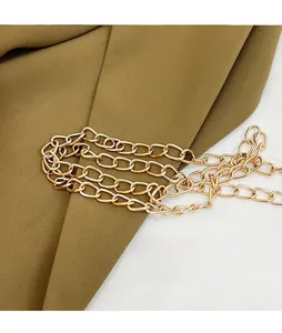 Detailed close-up of golden metal chain strap with polished finish on green fabric