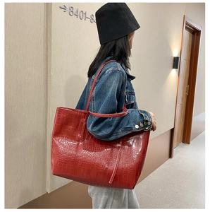 Détail du sac cabas rouge texture crocodile avec fines bandoulières et finition brillante