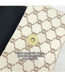 Close-up of golden round buckle and vintage monogram pattern on white leather bag