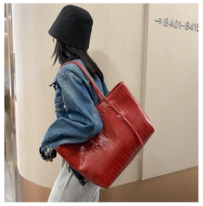 Détail du grand sac cabas marron rouge à motif crocodile porté par un mannequin