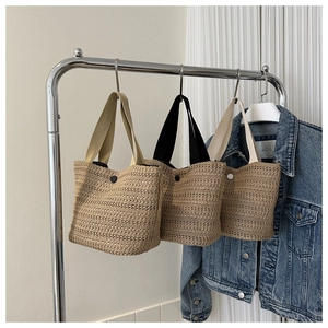 Détail de sacs seaux en paille tissée avec fermeture à bouton et anses en tissu coloré