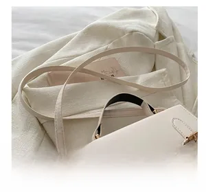 Detail of cream leather messenger bag with gold buckle and adjustable shoulder strap