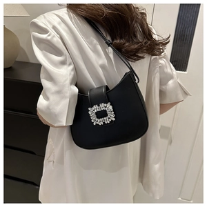 Gros plan sur la boucle carrée en strass de ce sac demi-lune en cuir noir poli