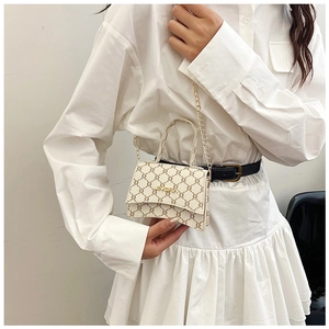 Detail of mini crossbody bag with brown geometric pattern and gold chain strap