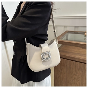 Detail of elegant off-white leather shoulder bag featuring a sparkling crystal buckle