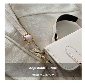 Close-up of cream leather shoulder bag with adjustable strap and golden metal buckle