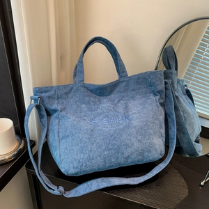 Light blue corduroy tote bag with FASHION embroidery shown in a lifestyle setting