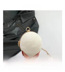 Detail of round pearl white hard shell clutch with gold ring handle and chain strap