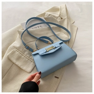 Detail of light blue crossbody bag featuring a gold chain on soft leather material